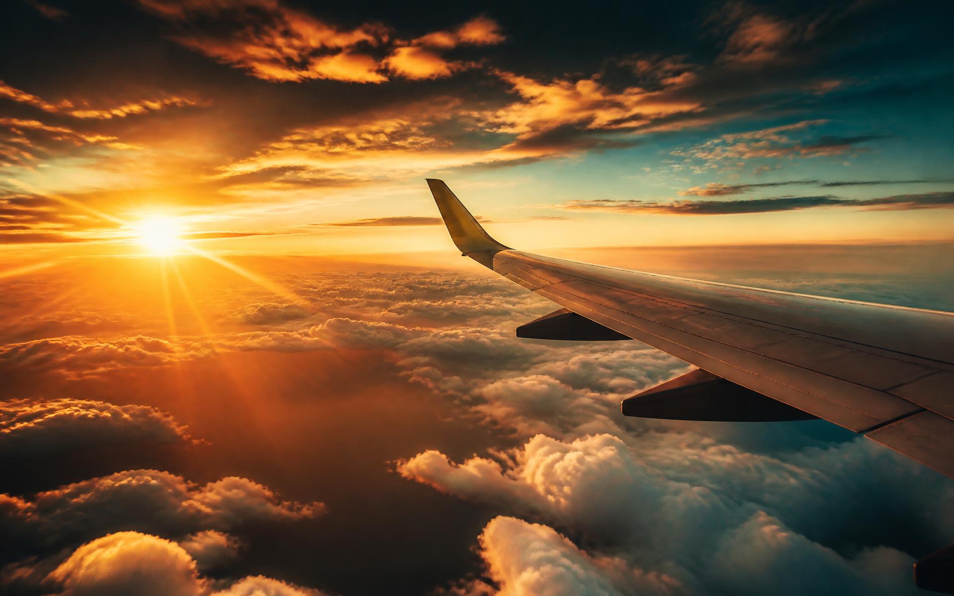 View of an airplane wing above golden sunset clouds